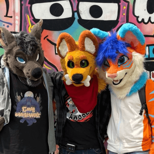 Luh and two other suiters left and right with him infornt of graffiti